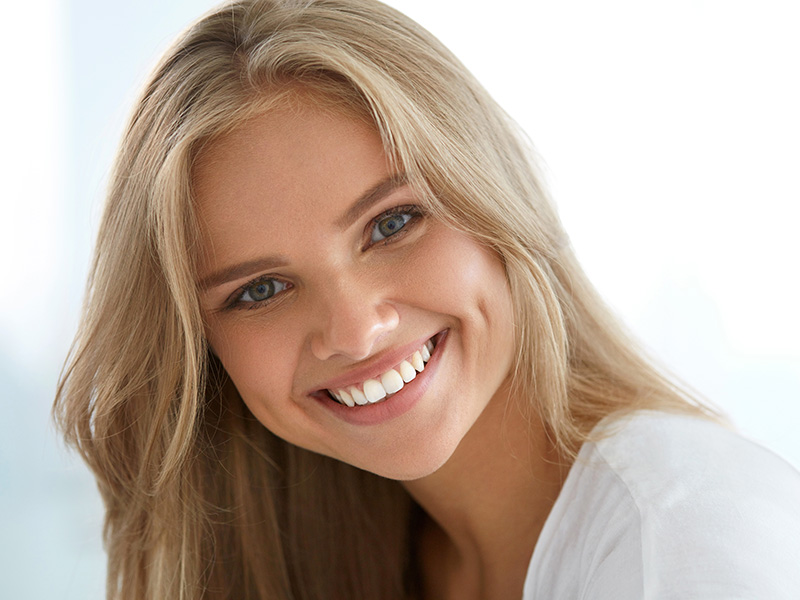 Smiling woman with blonde hair, set against a blurred background.