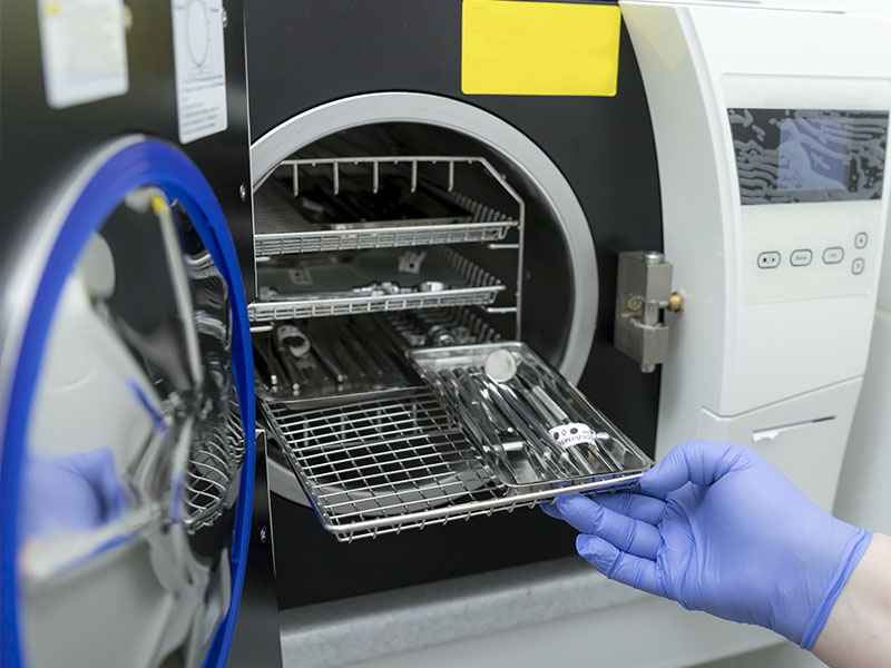 Person in blue gloves opening a drawer with various tools in an industrial setting, focusing on a piece of equipment.