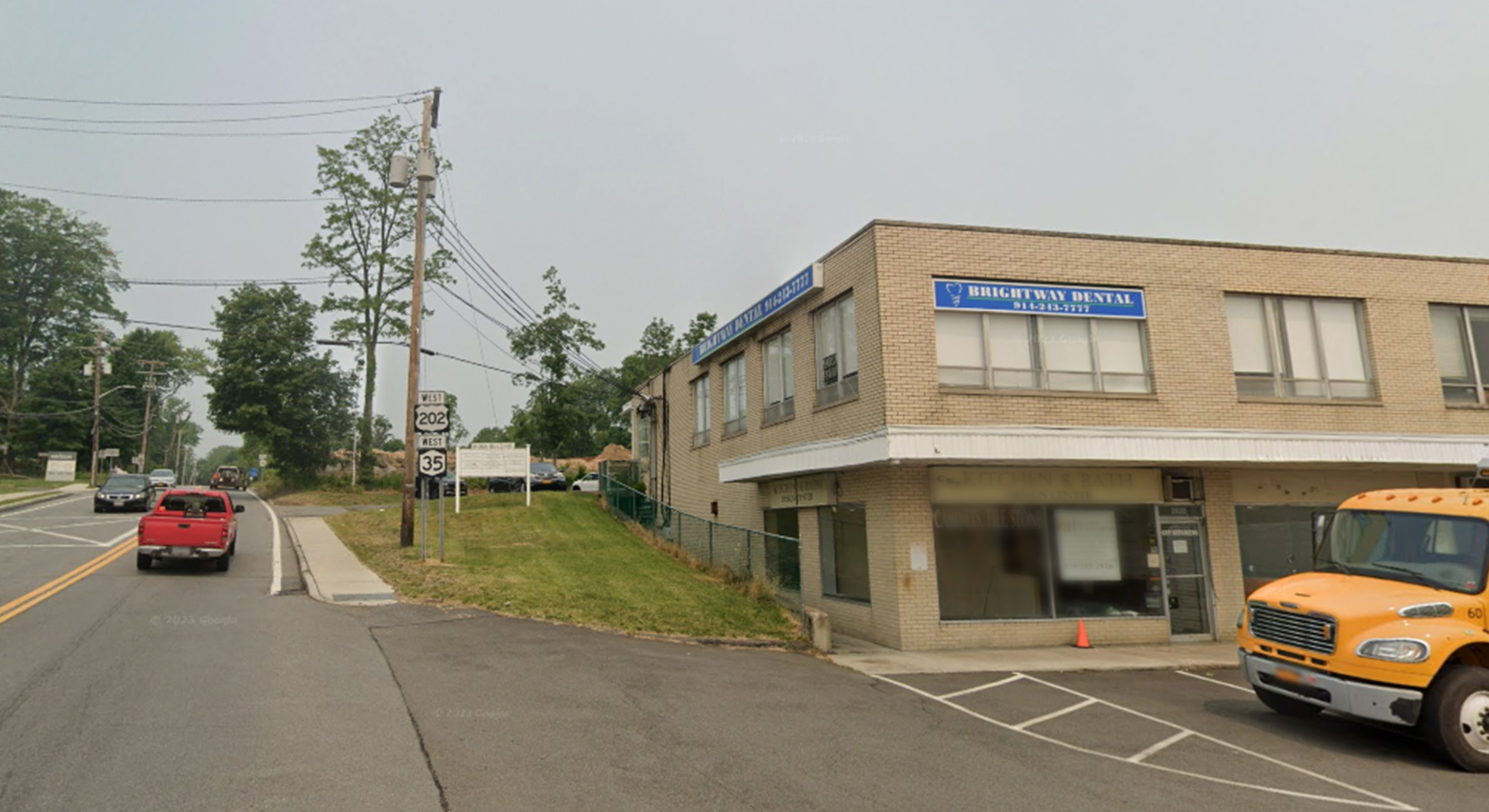 The image shows a commercial building with a sign indicating it's an office, parked vehicles, and a clear sky.
