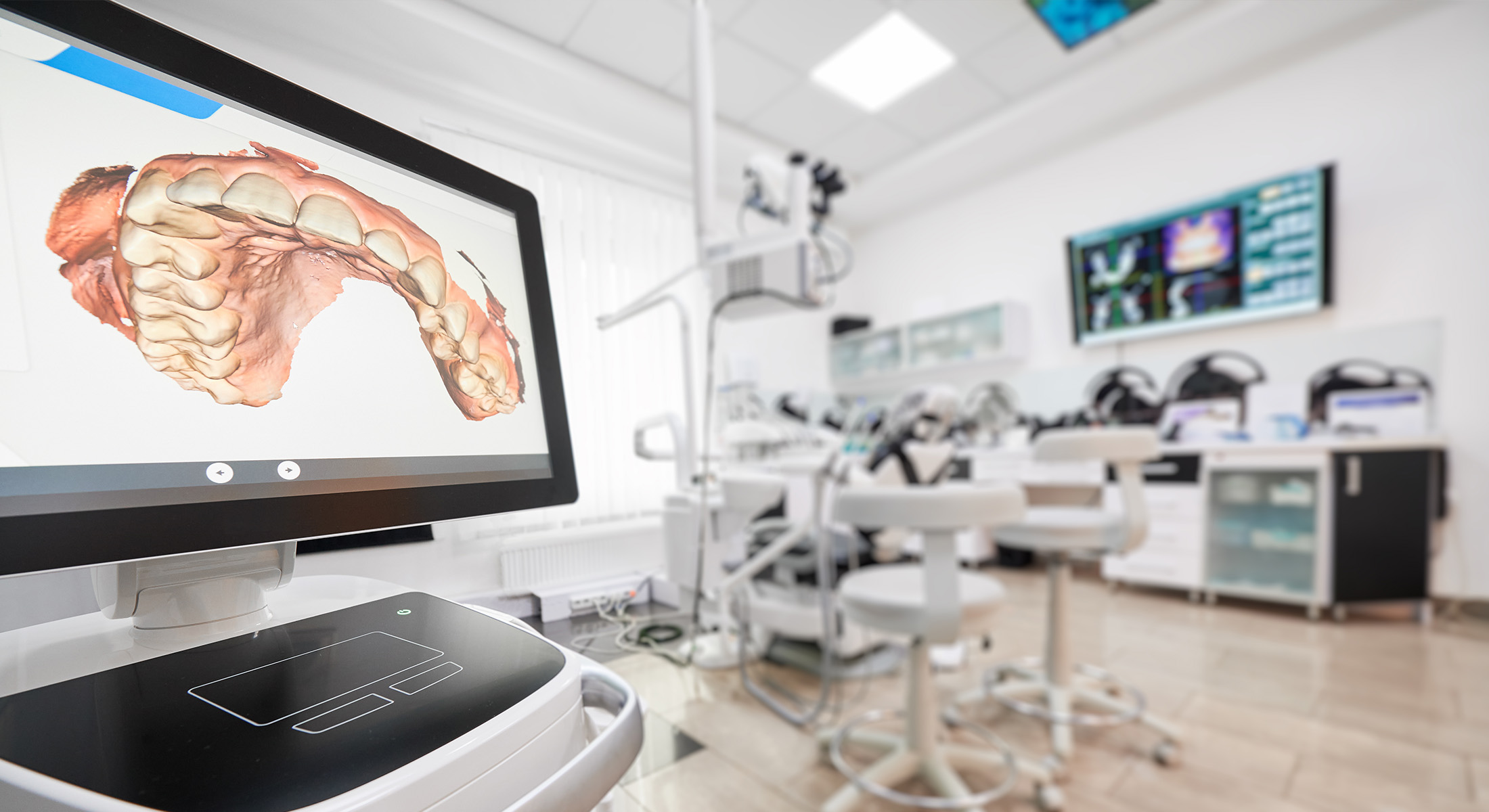 A modern dental office setting with a large monitor displaying an image of a human mouth.