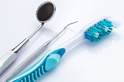 The image shows a collection of dental tools, including a toothbrush and a pair of tweezers, displayed on a white background.