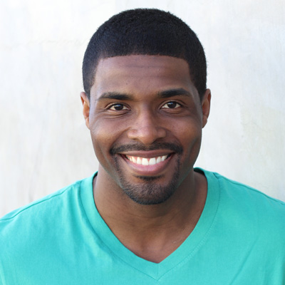 An elderly couple posing for a photo with smiles, one of them is wearing a scarf.
