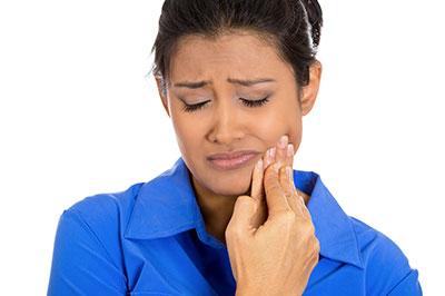 A woman in a blue shirt is holding her finger to her mouth, appearing to be concerned or contemplating.