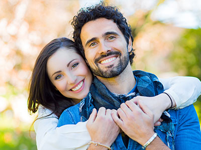 The image features a man and a woman embracing each other, with the man wearing a scarf around his neck.