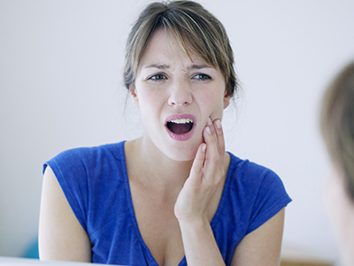 Woman with surprised expression, holding her hand to her mouth.