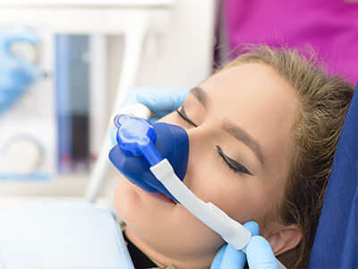 A woman receiving oxygen therapy through a medical device, with a healthcare professional assisting her.